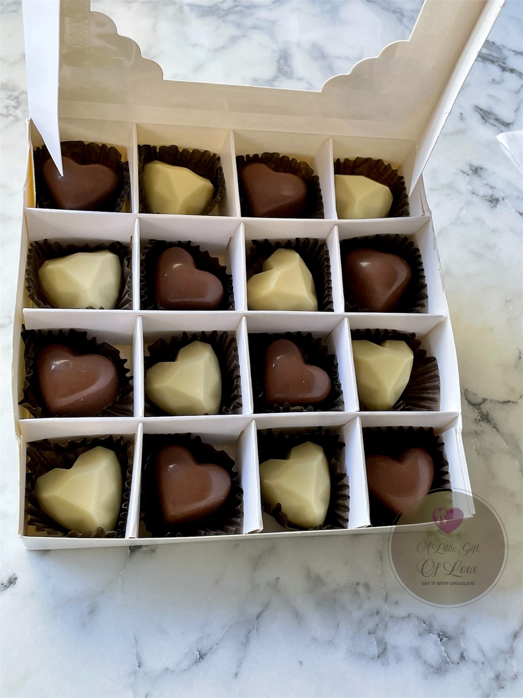 A gift box containing a selection of milk and white heart shaped chocolates.