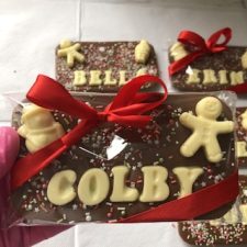 A milk chocolate bar topped with recipients name, festive chocolate shapes and sprinkles.