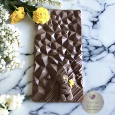 A luxury milk chocolate bar embellished with a pink or yellow chocolate flower and and cute chocolate teddy holding a bunch of flowers.